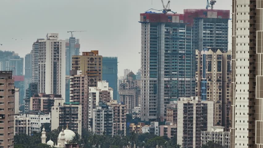 Aerial view of the Mumbai city skyline during the monsoon season near Atal Setu, Sewri, Mumbai, India. The dramatic drone perspective captures rain clouds, misty atmosphere.