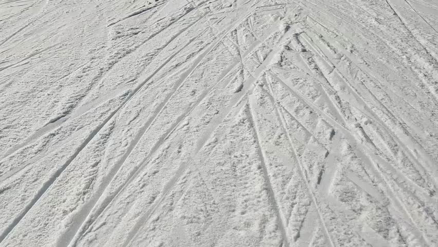 High Angle View of Snowy Ground Texture on a Ski Piste with Numerous Ski and Snowboard Tracks Crossing Each Other in Bright Sunlight for Winter Backgrounds