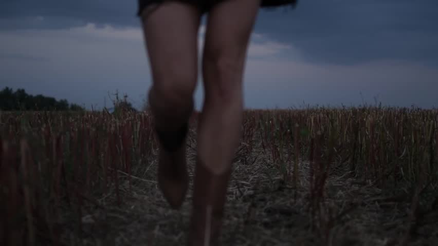 Woman Walking Through Harvested Field at Sunset