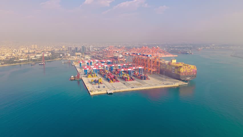 Aerial drone shot with diagonal left movement over industrial port in Mersin, Turkey with light fog