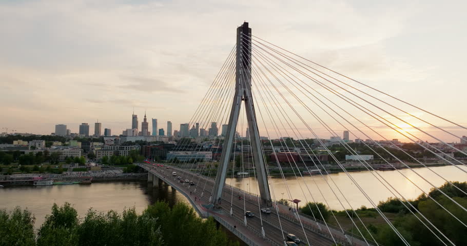 Warsaw skyline and Holy Cross Bridge at sunset. Cinematic riverfront with iconic Poland Capital city landmarks, perfect for travel and urban visuals. Wide angle Establishing 4K drone orbit shot