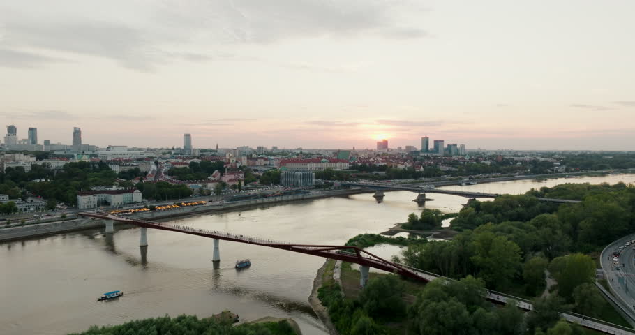 Aerial view of Warsaw along the Vistula River showing few bridges and distant skyline. Panoramic cityscape overview at golden hour, ideal for urban travel. Extreme wide 4K drone establishing shot 