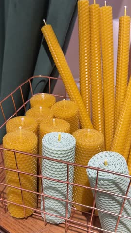 honey with dipper and lightning beeswax candle on pale yellow background, closeup