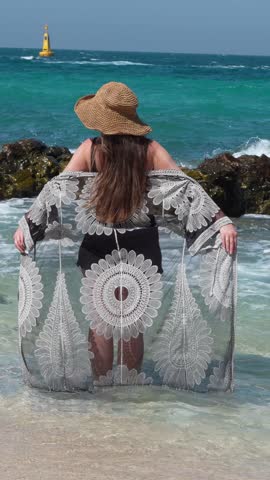 Back View of Elegant Woman in Beachwear Standing in Ocean Waves