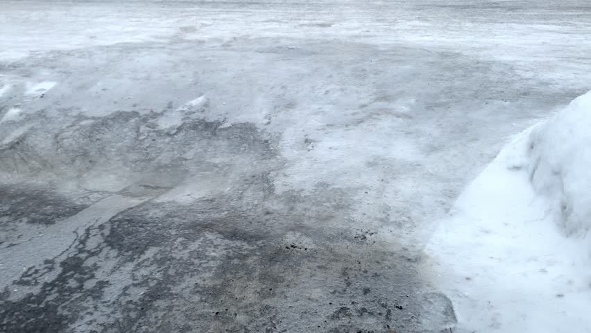 Sheet of ice covering residential driveway after freezing rain in winter, showing hazardous icy conditions and slippery surface, Ottawa, Canada