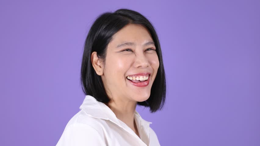 Woman with short black hair smiles warmly, seated in office chair, under bright studio lighting