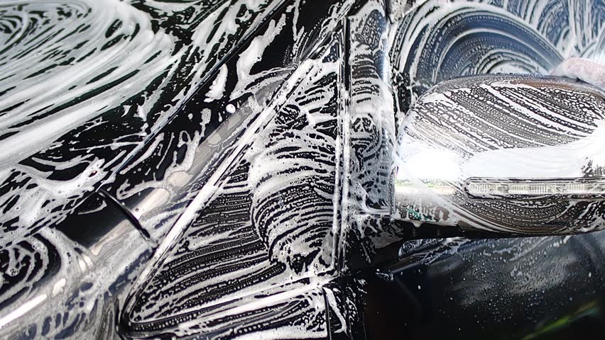 Hand Washing Black Car with White Soap Suds and Bubbles on Side Mirror