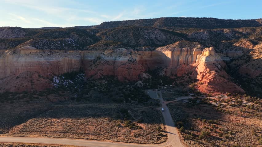 High-end drone footage lowers and flies toward massive, multicolored canyon walls in the Southwest desert. Captures dramatic geological layers and rugged terrain. Ideal for documentary openings.