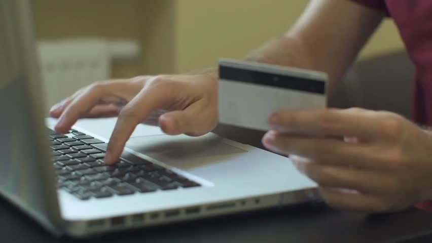 Close-up of a man paying for online shopping using a laptop and credit card, demonstrating secure digital payments and e-commerce transactions.