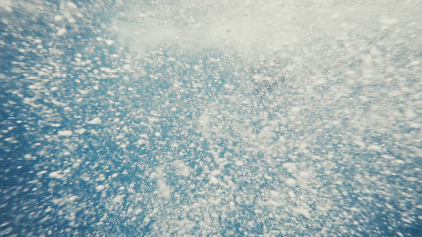 Humpback whale dives into deep ocean as bubbles and mist swirl underwater in slow motion
