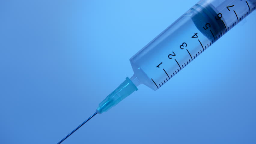 Injection syringe with medicinal solution on blue background close-up, pharmacology, drug development, scientific medical research