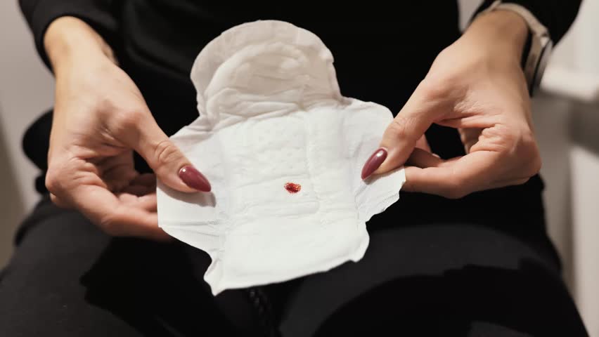 Detailed close view shows small red blood drop on clean white sanitary pad