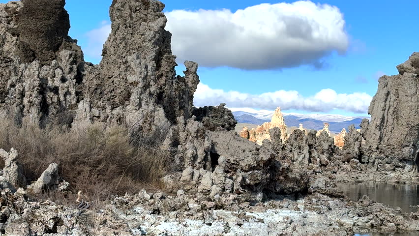 Slow pan across shoreline of Mono Lake, revealing the intricate and porous textures of the South Tufa towers, Sierra Nevada emerge in distance, framing landscape within Mono Basin, California, USA