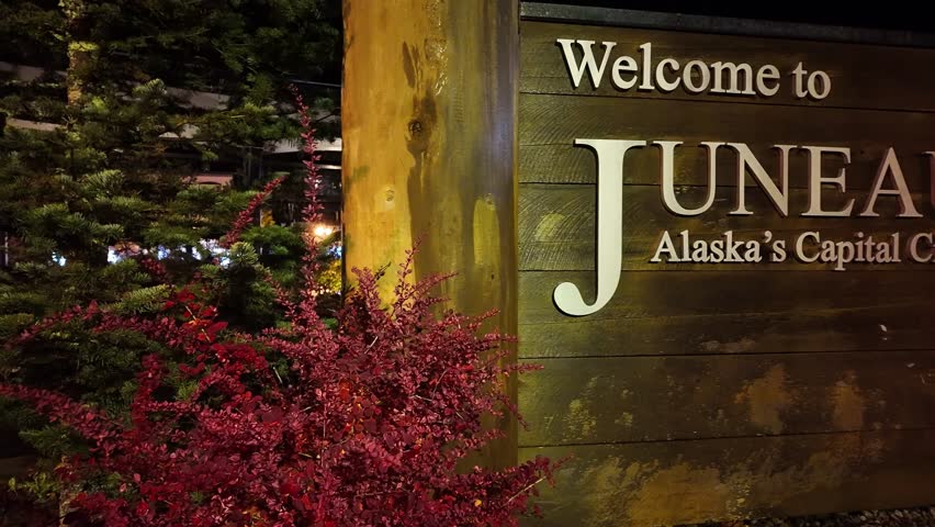 Gimbal close-up panning shot of signage welcoming visitors to Juneau at night in Southeast Alaska. 4K