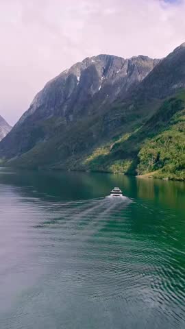 A boat or ferry in the fjord near Viking Valley at Gudvangen, Norway - pull back aerial flyover 4k