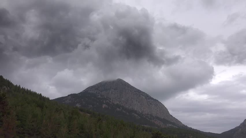 Time lapse of dark clouds collecting on mountain peaks in Balkan range Southeast Europe. Dramatic weather with moist air over forested terrain creating moody atmosphere.