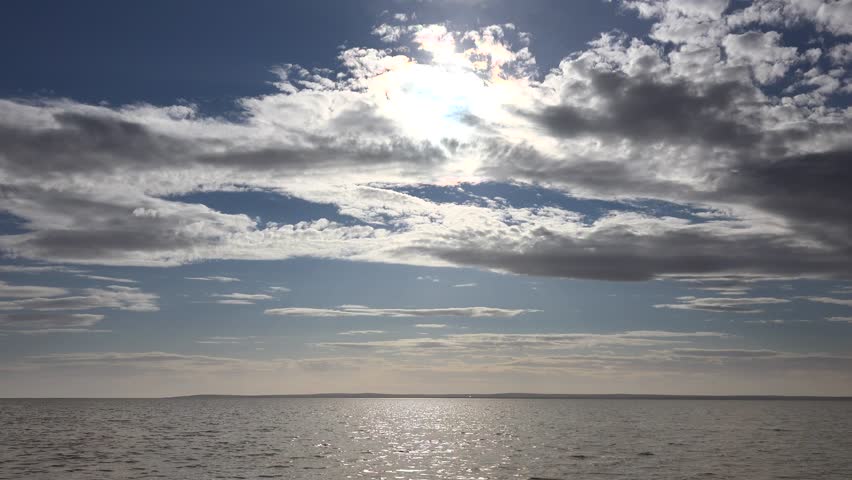 Time lapse view of mixed cloudy sky over Lake Baikal in Russia Siberia region. Dramatic cloud formations with sunlight creating atmospheric natural scenery above water surface.