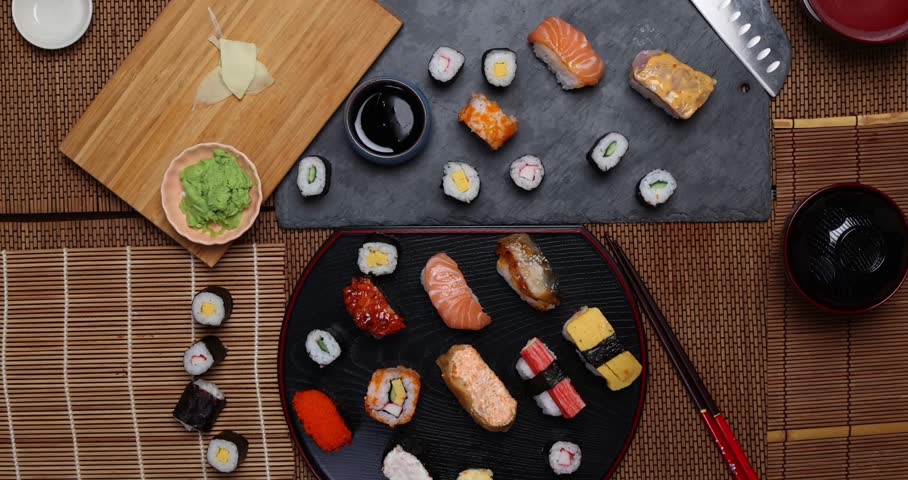 High-quality close-up of fresh assortment sushi rolls served on a dark plate, featuring vibrant colors, fresh fish, laid on slate board bamboo mat chopsticks  