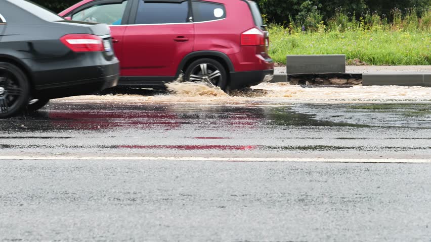 Driving cars splashing water while commuting on a wet road during a rainy day