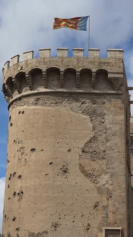 view of The flag of Valencia (Reial Senyera)  and the Torres de Quart (Quart Towers), one of the two remaining gates of the old city wall of Valencia, Spain.