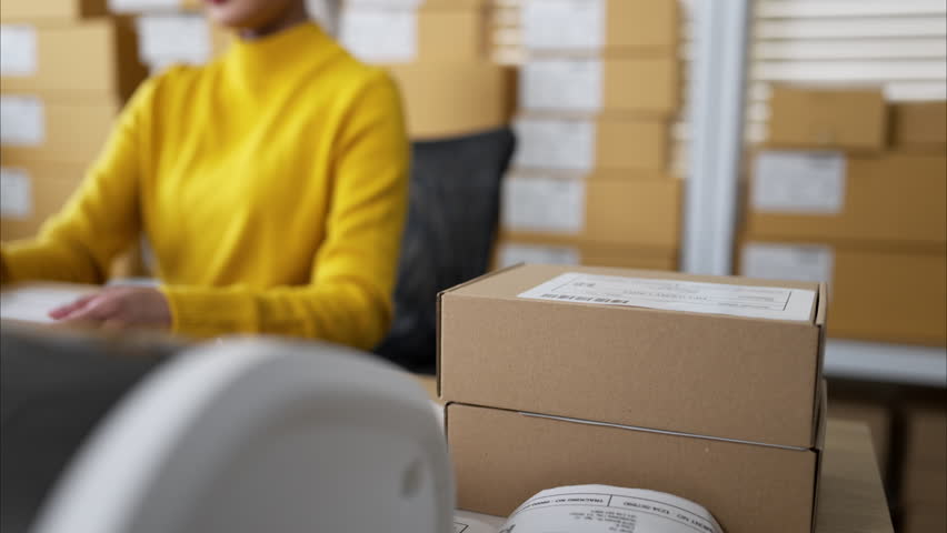 Small business owners packing boxes and preparing shipping labels together in warehouse office