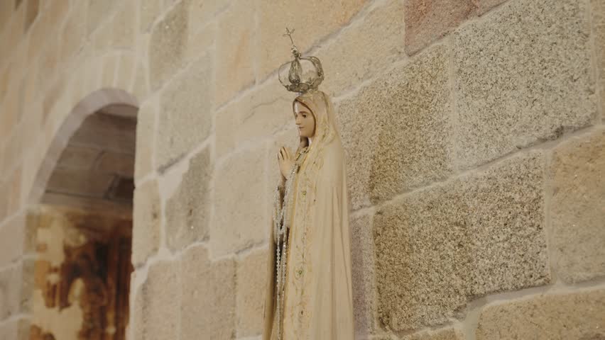 Religious Virgin Mary statue with crown attached to stone church wall