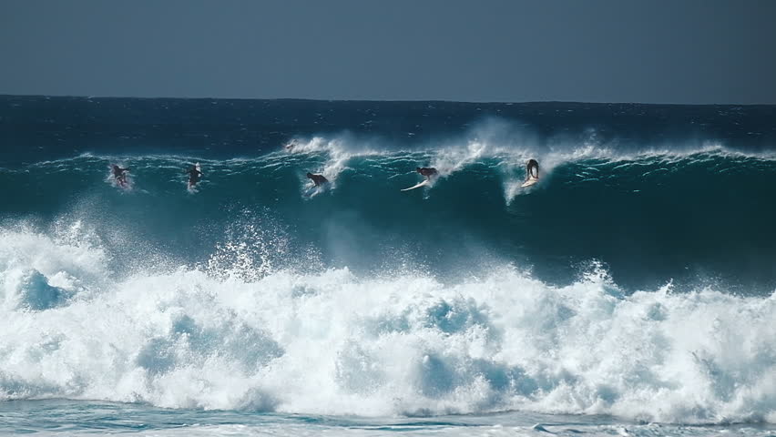 Big wave surfing in Hawaii on Waimea Bay. People surf the huge ocean wave breaking on the Hawaiian shore in Waimea Bay. Surfers share the wave in Hawaii. Oahu island
