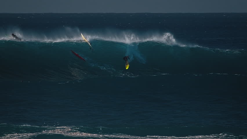 Big wave surfing in Hawaii on Waimea Bay. Person surfs the huge ocean wave breaking on the Hawaiian shore in Waimea Bay. Surfer rides the big wave in Hawaii. Oahu island