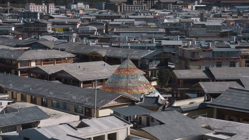 A dense cluster of Tibetan-style rooftops surrounds a vibrant prayer stupa in Shangri-La, revealing the unique blend of urban life and traditional Buddhist culture.