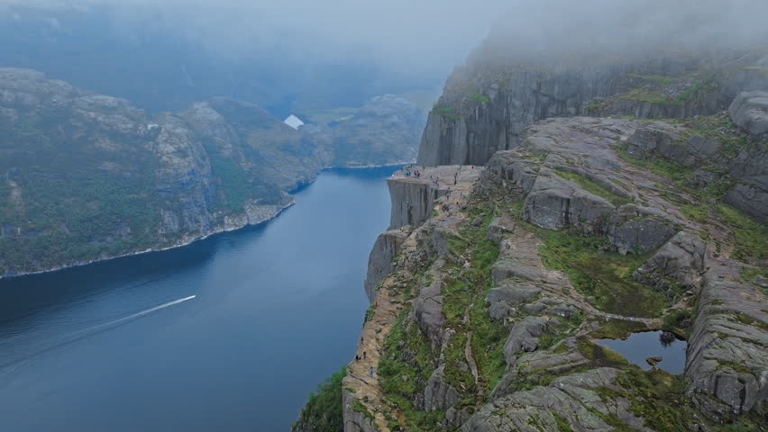 Lysefjord seen from Pulpit Rock Preikestolen. The camera glides along the cliff edge, revealing calm fjord waters far below during a peaceful hiking experience.
