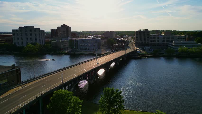 An aerial shot showcases the vibrant cityscape of Rockford, Illinois, with a prominent bridge spanning a wide river.