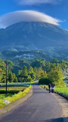 Beautiful Sunrise View of Mountain with Lenticular Clouds over Green Agriculture Fields.