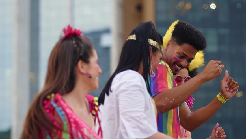 Joyful group of friends performing choreography at Brazilian Carnival celebration. Happy people in colorful outfits dancing together during a traditional street festival