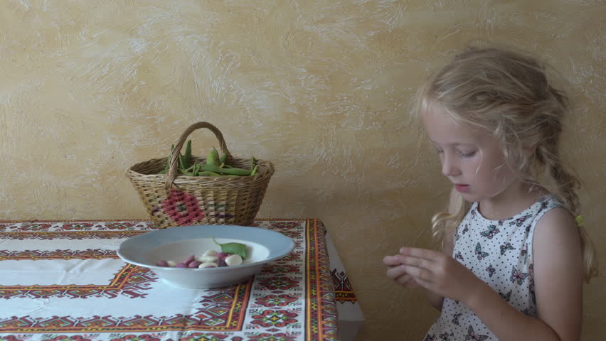 little girl peels beans from pods, Child helps in kitchen, cleaning green beans