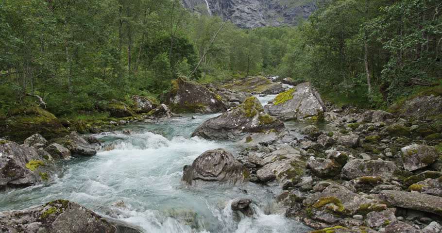 Rushing mountain river flowing through norwegian forest landscape