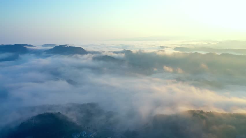 A stunning collection of sunrise and sea of clouds videos showcasing mountain peaks and forests shrouded in morning mist. These breathtaking timelapse and aerial drone shots capture the magical golden hour light as the sun rises above cloud inversions, painting the sky in vibrant hues. The footage features tranquil scenes of mountain tops emerging from thick clouds, with misty forests and distant mountain ranges creating a serene, ethereal atmosphere. Perfect for illustrating themes of nature, tranquility, and natural beauty, these visuals evoke a sense of awe and peace. Ideal for travel promotions, landscape portfolios, nature documentaries, and meditation content, the videos highlight the dramatic contrast between golden sunlight, soft clouds, and dark mountain silhouettes, creating a powerful and inspiring natural spectacle.