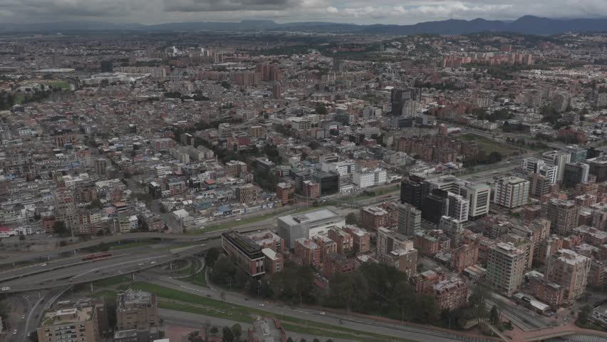 Bogotá, Bogotá D.C., Colombia – July 2024:
High-altitude aerial view of Bogotá, Colombia, displaying a vast cityscape of residential zones, commercial districts, and green corridors. The cloudy sky and distant hills frame the capital’s extensive urban development.
