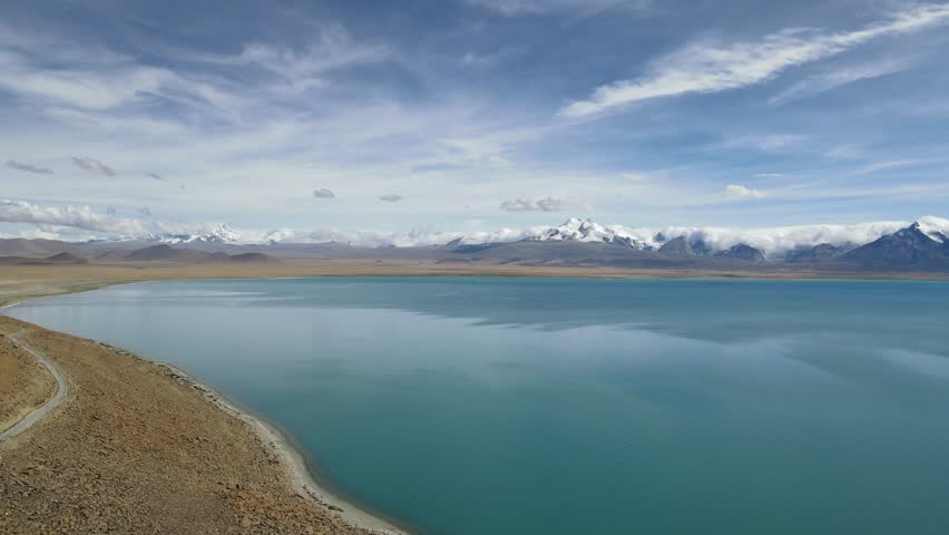 Drone flying over plateau lake with Shishapangma mountain on Tibetan Plateau, China