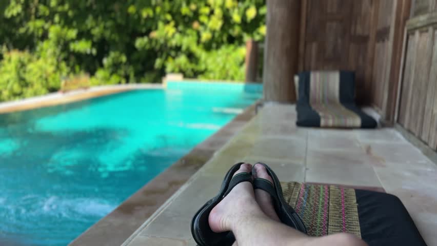 Panning view across private swimming pool at luxury ocean villa on Koh Yao Yai island in Thailand showing blue water, lush tropical forest and calm resort atmosphere.