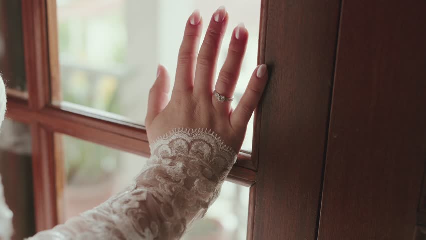 Close view of bride hand wearing ring touching wooden window