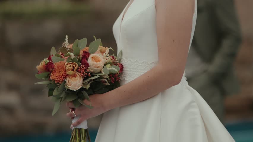 Close view of bride holding bouquet over white wedding dress