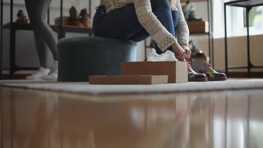 Female customer trying on shoes while shopping for footwear in shoe store. Young woman trying on modern shoes in shoe store. woman trying on shoes while shopping in shoe store.