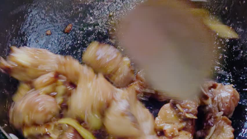 A close-up of a chef stir-frying pork ribs