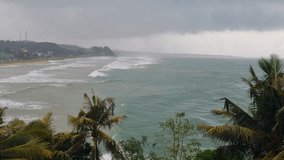 Wild Indian Ocean crashes against South Sri Lanka’s shore under monsoon clouds. Palm trees sway violently in the wind, capturing stormy weather, extreme conditions, and climate impact - Powered by Shutterstock - Get 15% off with code: PIKWIZARD15