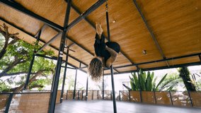 Flexible young woman with curly hair gracefully performing an upside down spin on a pole. An acrobatic dancer showcasing her strength and skill - Powered by Shutterstock - Get 15% off with code: PIKWIZARD15
