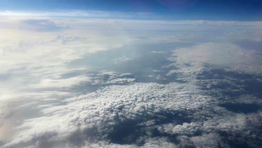 Dense layer of cumulus clouds, top view from an air plane side window during a flight at high altitude above of the clouds
