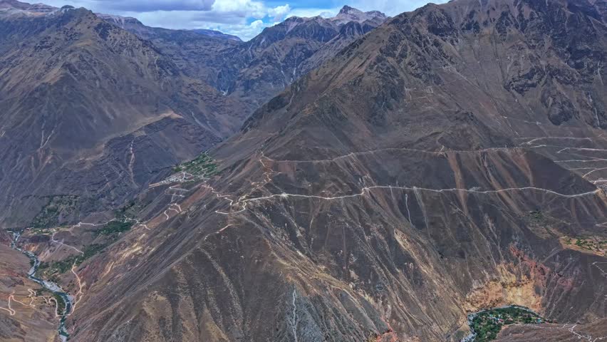 Drone pans the Colca Canyon mirador, revealing multiple valleys and ridges joining the canyon. The three-dimensional landscape highlights the canyon’s depth, rugged terrain, and epic Peruvian scenery