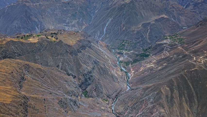 Drone captures sweeping panoramic shot of Colca Canyon, highlighting the famous mirador, Rio Colca, and iconic erosion formations. The dramatic cliffs and canyon floor emphasise Peru’s epic landscape.