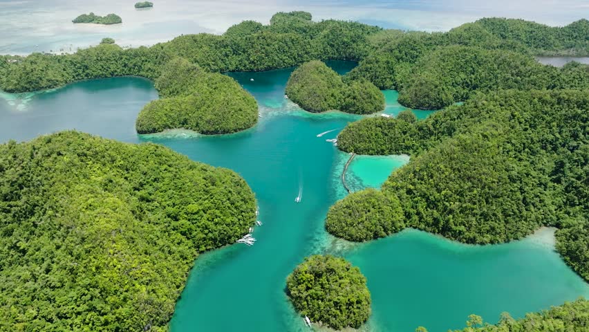 Lush islands surrounded by turquoise water with boats leaving trails across the lagoon surface. Sugba Blue Lagoon. Siargao, Philippines.