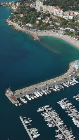 4K aerial vertical video of Port of Cap d'Ail marina and Plage Marquet beach bordering Monaco. Cinematic drone footage of French Riviera coastline and yachts. Scenic travel view for mobile.